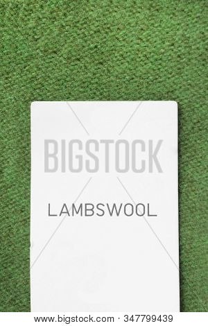 Clothes Label Says Lambwool On Green Knitted Background Closeup