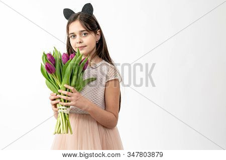 Confident, Calmy Brunette Girl In Beige Dress Holds Purple Flowers In Her Hands And Looking At The C
