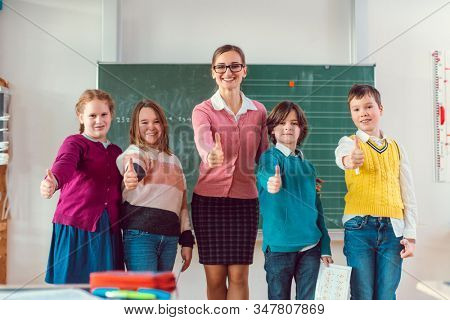 Thumbs up given by pupils and teacher because school is great and education important