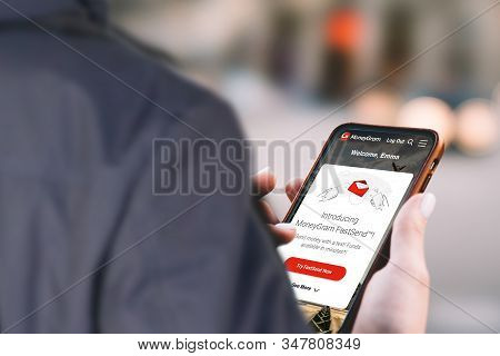 Man Holding Mobile Phone Showing Moneygram App And Money Transfer Service