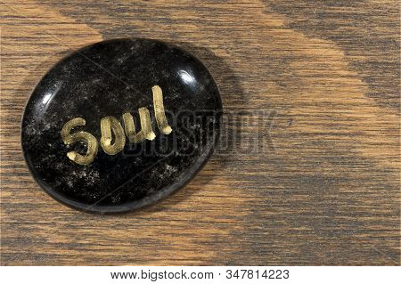 Healing Stone With Painted Soul Word On Wooden Background