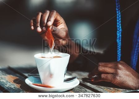 Close-up View Of Hands Of A Young Black Female Putting Sugar To A White Ceramic Cup With A Delicious