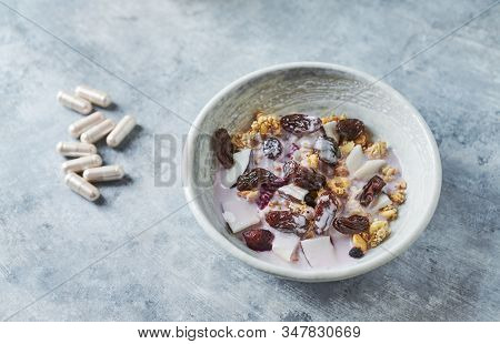 Bowl Of Granola With Yogurt, Nuts, Cranberry And Cocoanut. Sport Supplements ( Carnitine Capsules ) 