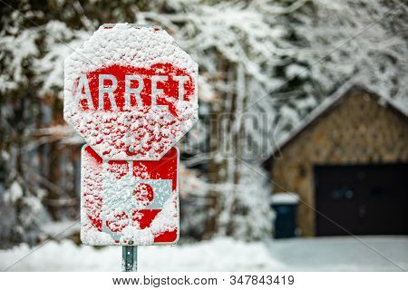 A Selective Focus Shot Of A French Canadian Traffic Control Sign Saying Stop, Covered With Snow And 