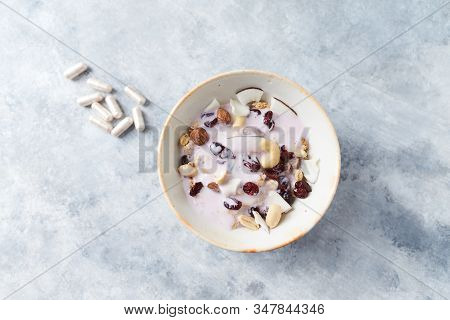 Bowl Of Granola With Yogurt, Nuts, Cranberry And Cocoanut. Sport Supplements ( Carnitine Capsules ) 