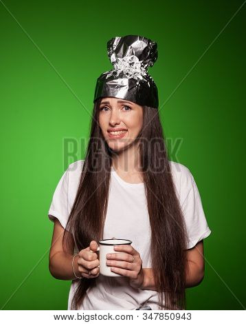 Attractive Young Woman Wearing Tinfoil Hat For Protection. Conspiracy Theory Concept. Woman Holding 