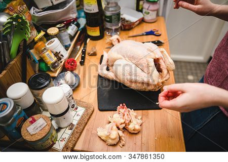 Paris, France - Dec 24, 2019: Woman Removing Fat From Fresh Capon Chapon Cockerel Meat On Kitchen Wo