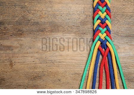 Top View Of Braided Colorful Ropes On Wooden Background, Space For Text. Unity Concept
