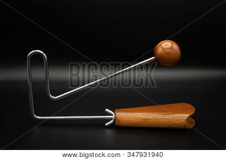 Closeup Of A Vibraslap Silver, Brown Wood On Black Underground