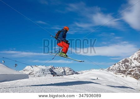 Male Skier Jumps In Snow Park In The Snowy Mountains Against The Blue Sky. Livigno, Italy