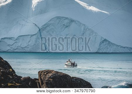 Orange Whale Watching Tour Boat Ship With Icebergs In Background. View Towards Icefjord In Ilulissat