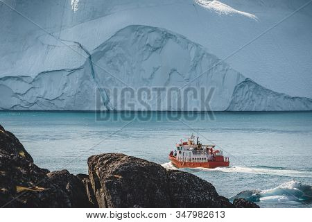 Orange Whale Watching Tour Boat Ship With Icebergs In Background. View Towards Icefjord In Ilulissat