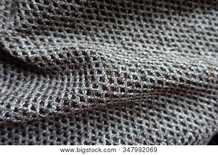 Closeup Of Greyish Brown Woolen Fabric With Diamond Pattern In Soft Folds