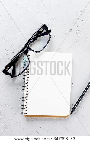 Empty Blank Notebook With Pen, Black Eyeglasses On Grey Background. Concept Work From Home, Financia
