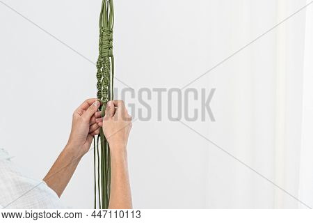 Handmade Green Macrame Plant Hangers With Potted Plant Are Hanging On Woman Hand. The Macrame Have P