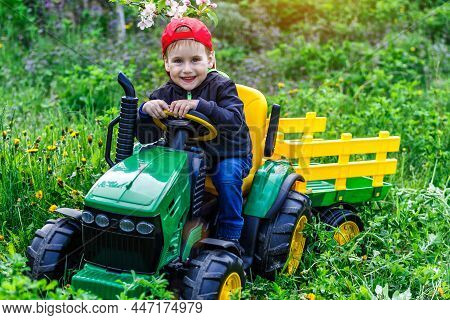 Ukraine Kiev 4 May 2019.a Child On His Little Tractor John Deere .portrait Of Young Boy In Nature, P