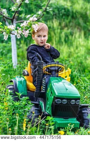 Ukraine Kiev 4 May 2019.a Child On His Little Tractor John Deere .portrait Of Young Boy In Nature, P