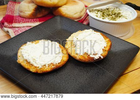 Toasted English Muffin Served Topped With Spreadable Cheese, Garlic And Herbs