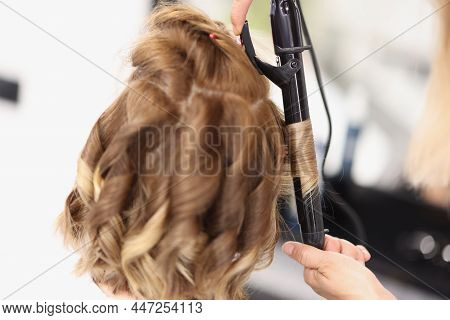Close-up Of Blonde Woman On Hairdresser Appointment, Master Use Curling Iron Tool For Waving Hair. B
