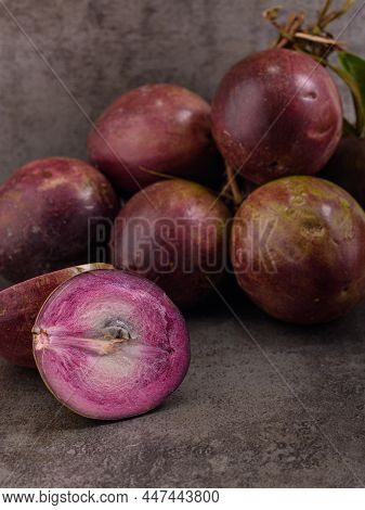 Photo Shows Several Purple Tropical Fruits. One Fruit Is Cut Open And The Inside Of It Is Visible. C