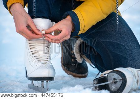 Young Woman Putting On Ice Skates. Female Hands Tying Laces. Close Up