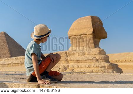 The Boy In Hat Sits In Front Of The Sphinx And Looks At It
