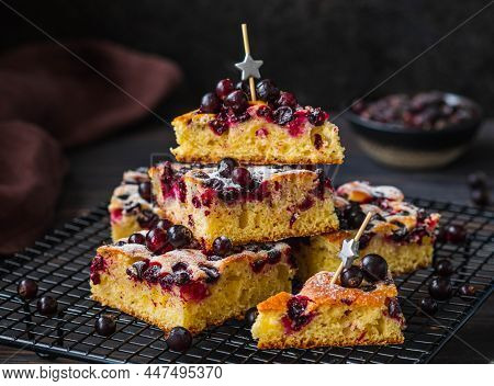 Sliced Sweet Blackcurrant Cornmeal Cake Sprinkled With Powdered Sugar On A Black Wire Rack On A Dark