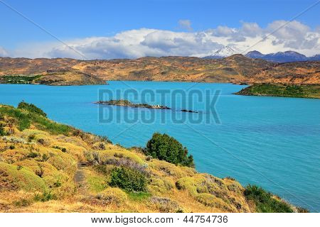 Nationalpark-Chile - Torres del Paine. Azurblaue Wasser des Lake Pehoe zwischen grünen und gelben hügeligen coa