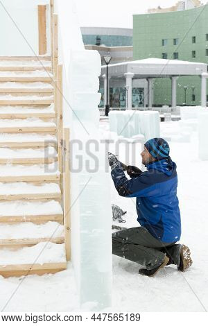 Sculptor In A Blue Winter Suit With A Chisel In His Hands At Work