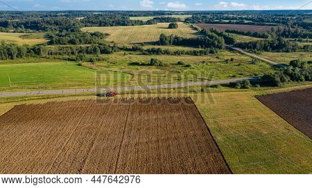 Scenic View Of Working Tractor In The Field Agricultural Field On A Summer Farm In The Evening. Aeri