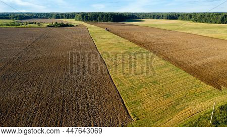 Scenic View Of Working Tractor In The Field Agricultural Field On A Summer Farm In The Evening. Aeri
