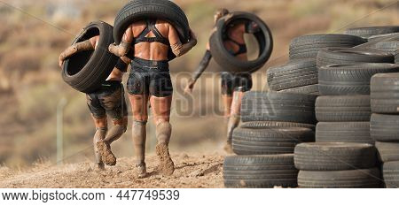 Mud Race Runners. Runners Carrying Tires In A Test Of The Race