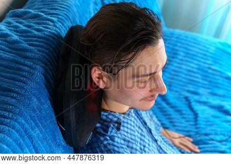 Electric Massage Cushion With Infrared Warming Areas. Milineal Man Relaxes At Home
