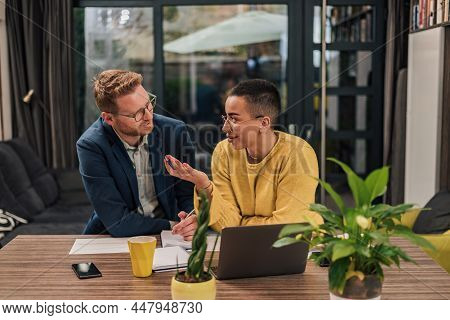 Smiling Couple Of Diverse Businesspeople Doing Paperwork Discussing And Working On Laptop Computer W