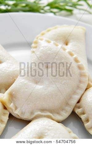 closeup of a plate with some uncooked spanish empanadillas, small meat or tuna pies