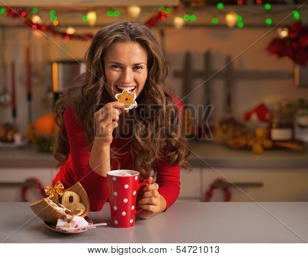 Happy Young Woman Having Eating Christmas Cookies In Kitchen