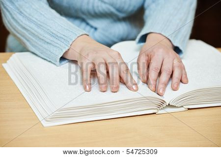 Blind or visually handicapped woman hands reading book written in Braille