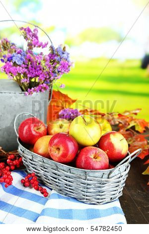 Juicy apples in basket on table on natural background