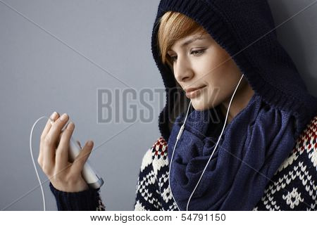 Young woman in hood talking on phone using earbuds