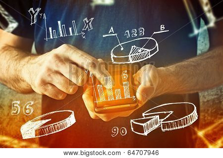 Man Using Mobile Phone With Drawings Of Charts And Other Infographics In Note Pad