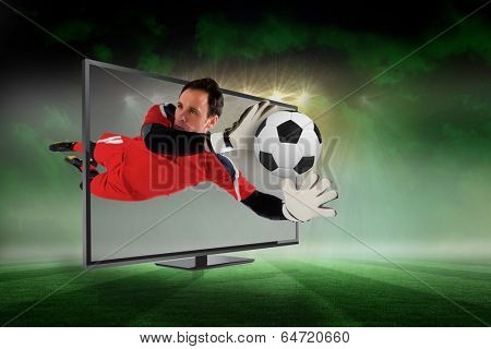 Composite image of fit goal keeper saving goal through tv against football pitch under green sky and spotlights