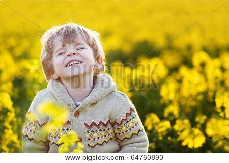 Happy Little Blond Toddler Boy Lauging In Yellow Rape Field On A Spring Day