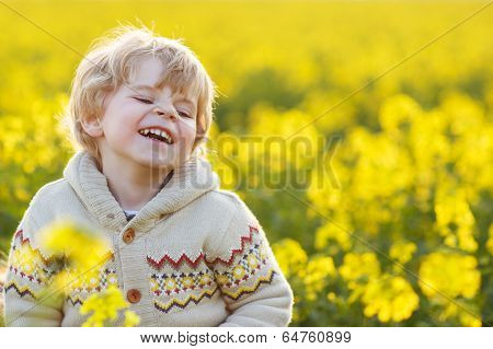 Happy Little Blond Toddler Boy Lauging In Yellow Rape Field On A Spring Day