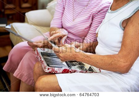 Cropped shot of elderly women feeling nostalgic and looking at old photographs