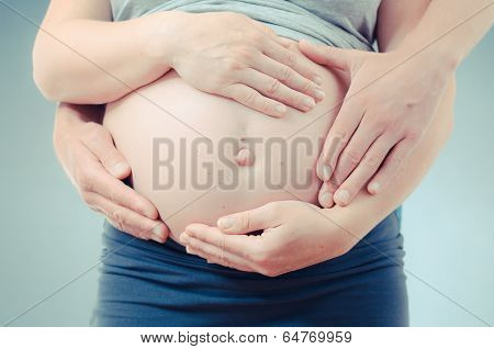 parents hands holding the mothers belly