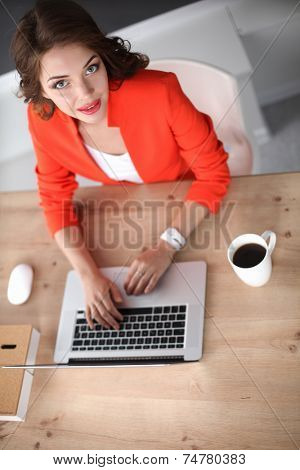 Attractive woman sitting at desk in office, working with laptop