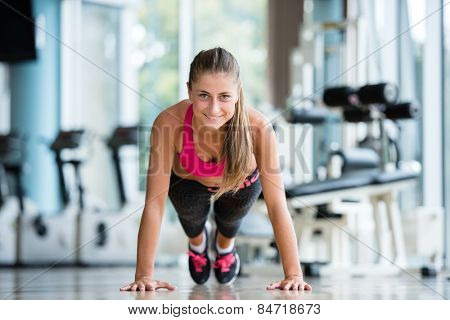 Gorgeous blonde woman warming up and doing some push ups a the gym