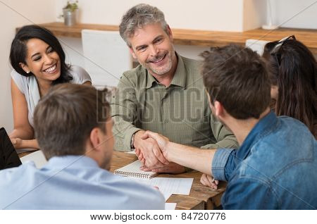 Smiling businessman looking at each other and shaking hands with new partner