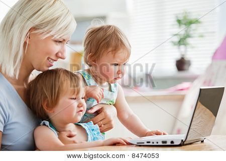 Bambini attoniti guardando un computer portatile con la loro madre