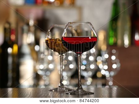 Two glasses of wine with bar on background